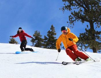 one person skiing and another snowboarding down a hill
