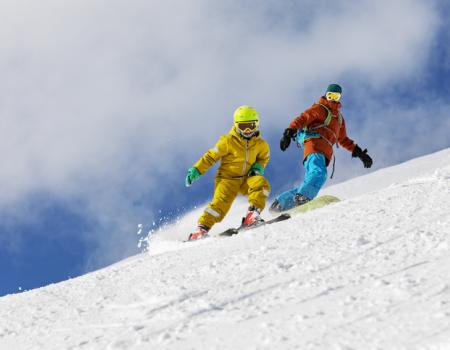 A parent and a child snowboard down a mountain slope